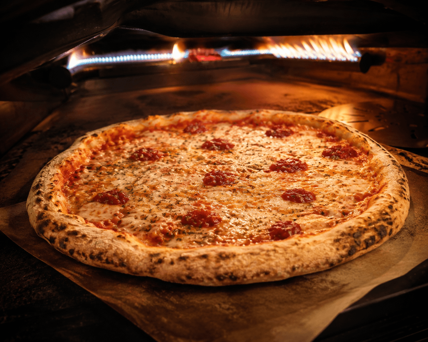 Pizza Sweet Margherita da Motzi no forno, com muçarela de búfala, tomate-cereja e borda dourada.